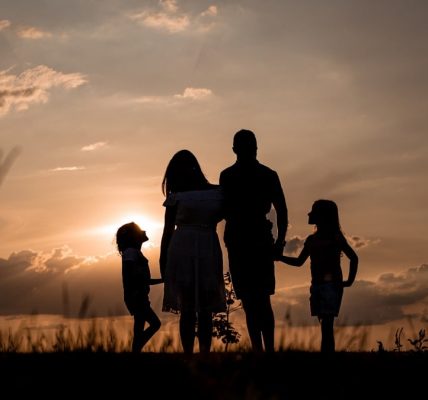 a family standing in a field at sunset